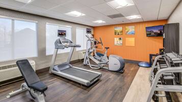 A gym with a treadmill, elliptical, and weight bench.