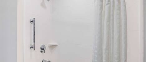 Un baño blanco con bañera, ducha y retrete.