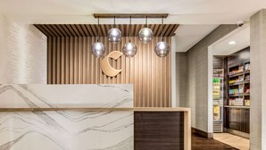 A reception desk with a marble design, a wooden slat wall, and a crescent moon decoration.
