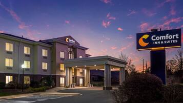 A Comfort Inn & Suites hotel with a covered entrance, multiple windows, and a clear sky.