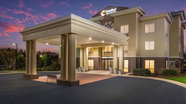 A hotel with a covered entrance, a sign for Comfort Inn & Suites, and a brick facade.