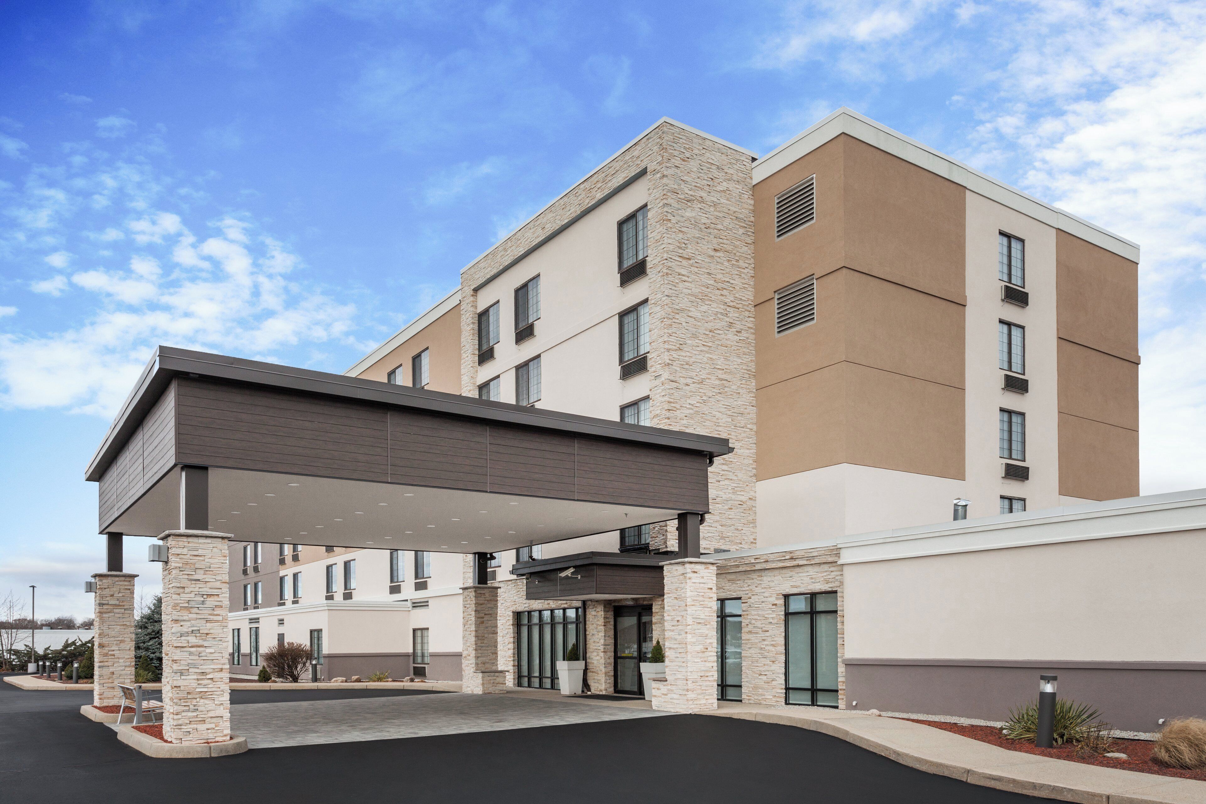 A multi-story hotel with a covered entrance and a parking lot.