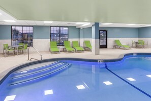 An indoor swimming pool with multiple lanes, green lounge chairs, and a seating area with tables. - Holiday Inn Express Hotel & Suites Providence-Woonsocket by IHG (Woonsocket)