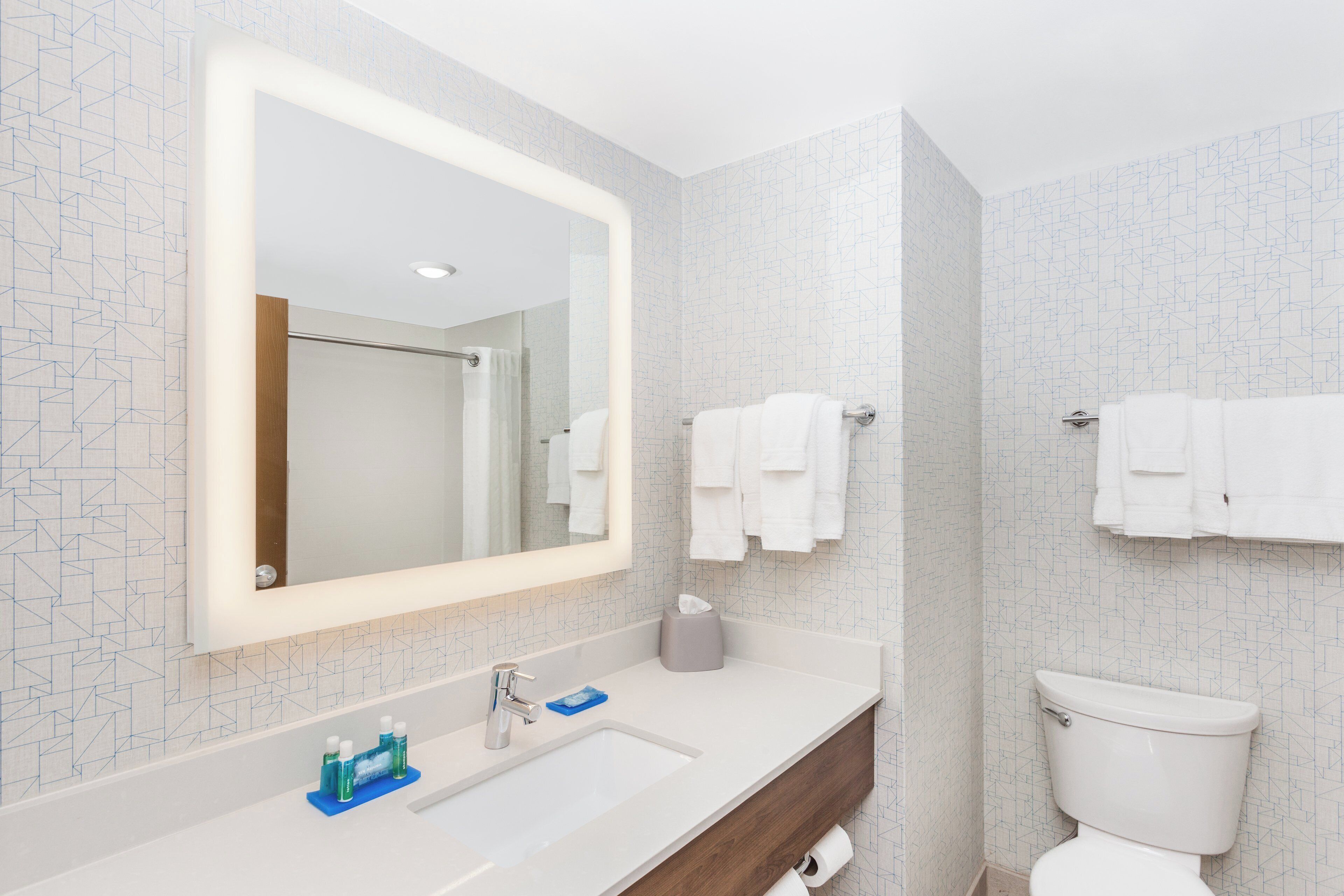 Une salle de bain moderne avec un grand miroir, un lavabo et des toilettes.