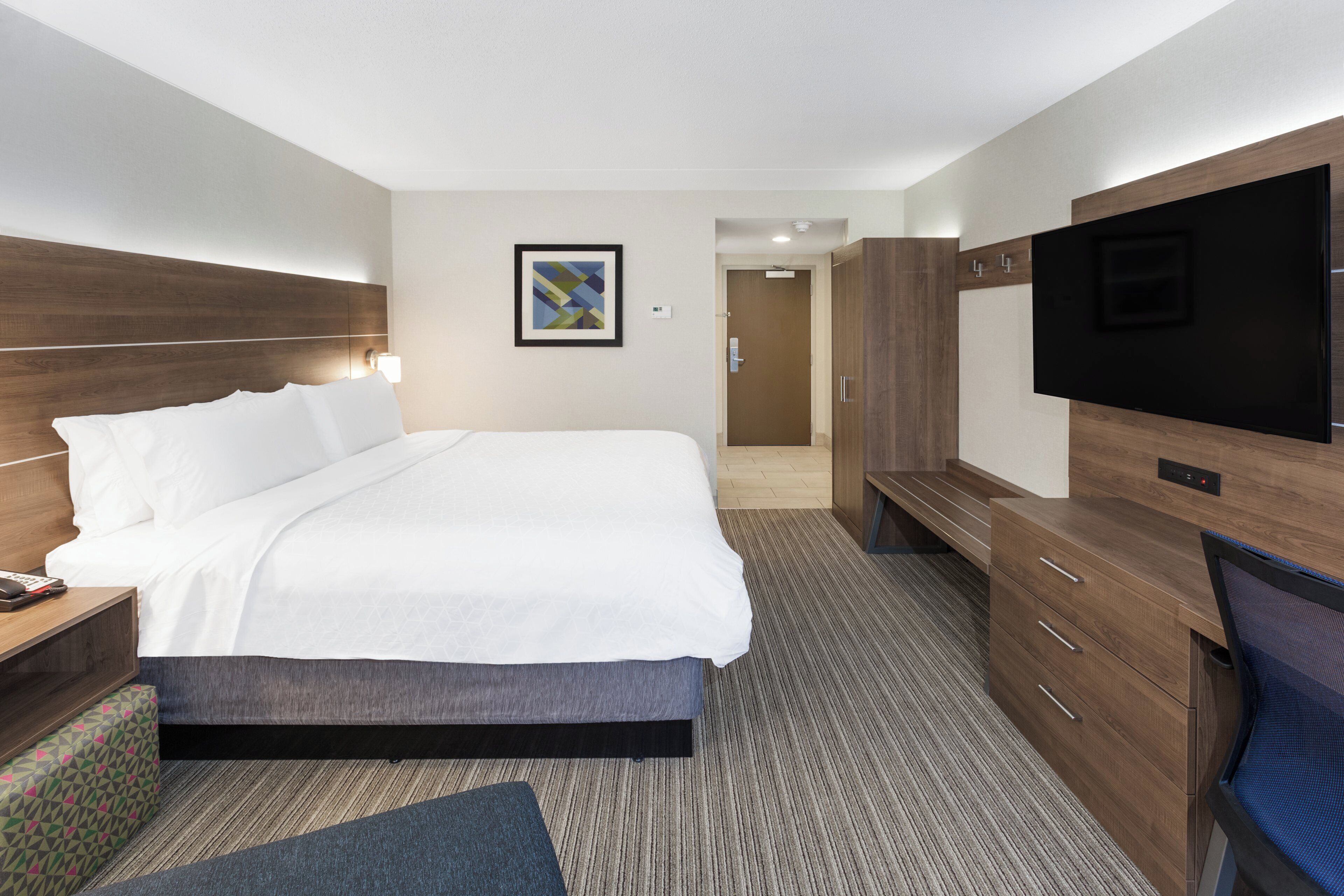A hotel room with a bed, a TV, a desk, and a wardrobe.