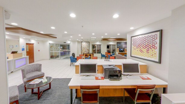 A modern office space with a reception desk, multiple workstations, and a large abstract painting. - Holiday Inn Express New Haven by IHG (New Haven)