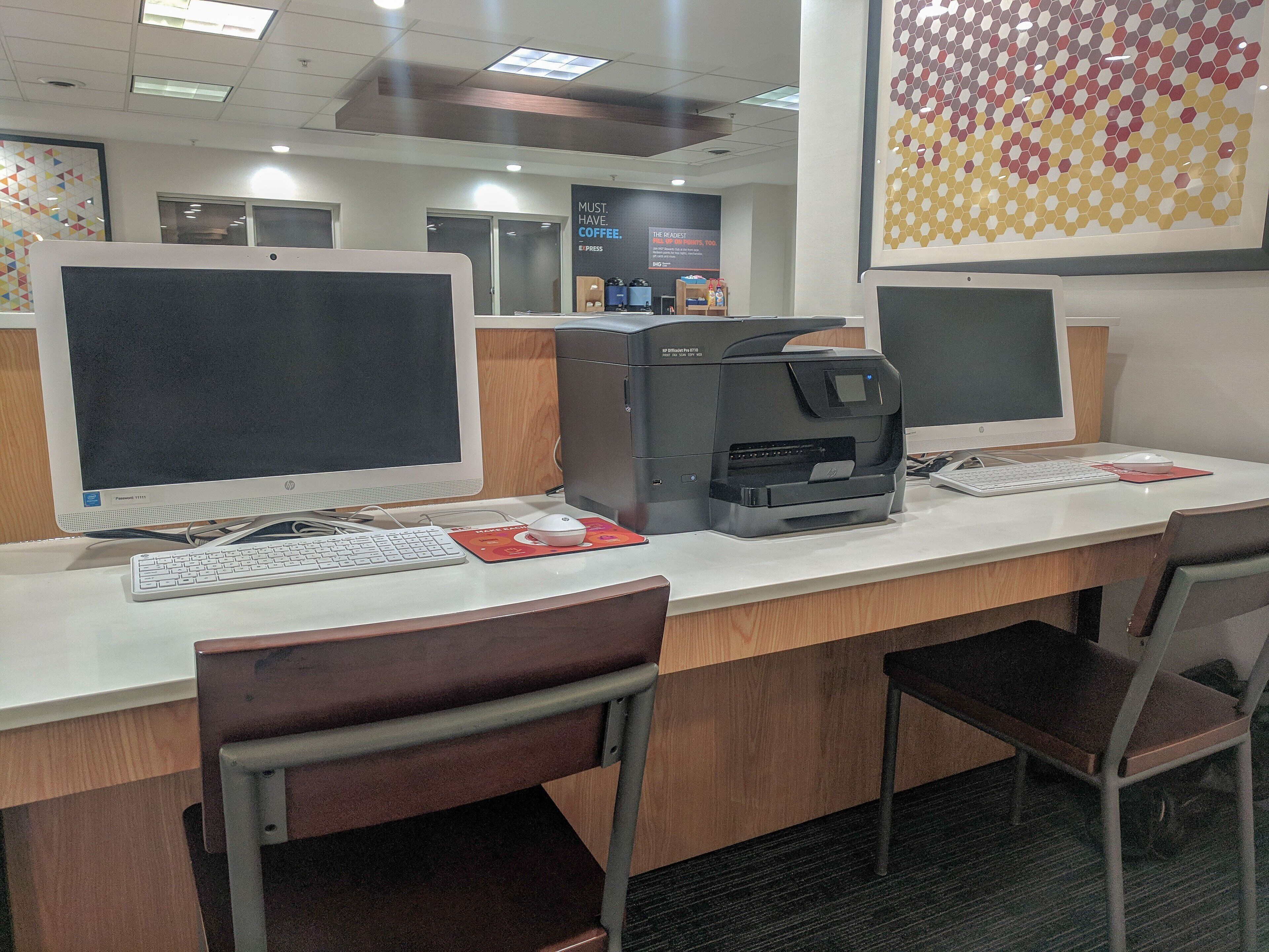 A computer station with a desktop computer, a printer, and a keyboard.