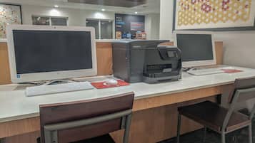 A computer station with a desktop computer, a printer, and a keyboard.
