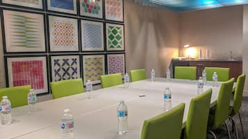 A conference room with a long table, green chairs, and water bottles.