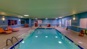 An indoor swimming pool with blue walls, orange lounge chairs, and a lifeguard on duty sign. - Holiday Inn Express New Haven by IHG (New Haven)
