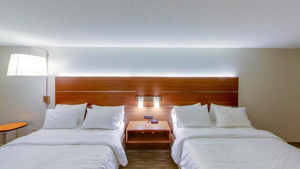 A hotel room with two beds, a nightstand, a lamp, and a wooden headboard. - Holiday Inn Express New Haven by IHG (New Haven)