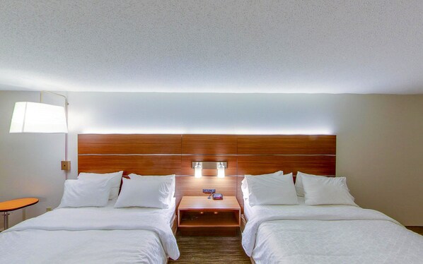 A hotel room with two beds, a nightstand, a lamp, and a wooden headboard. - Holiday Inn Express New Haven by IHG (New Haven)