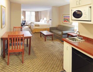 A hotel room with a bed, a sofa, a dining table, a kitchen area with a sink, and a microwave. - Holiday Inn Express Hotel & Suites Camden by IHG (Camden)