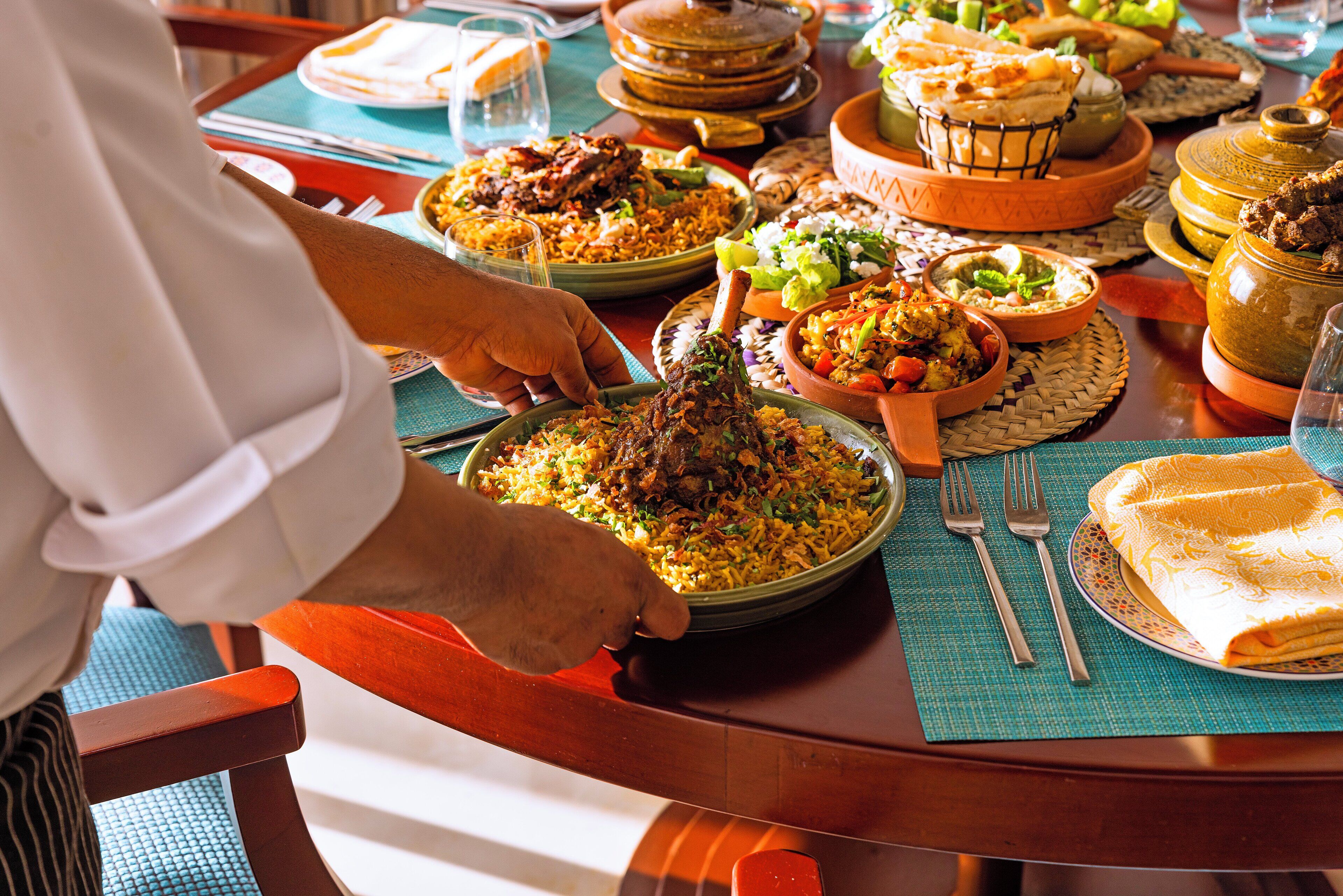 A dining table with various dishes and a person serving food.