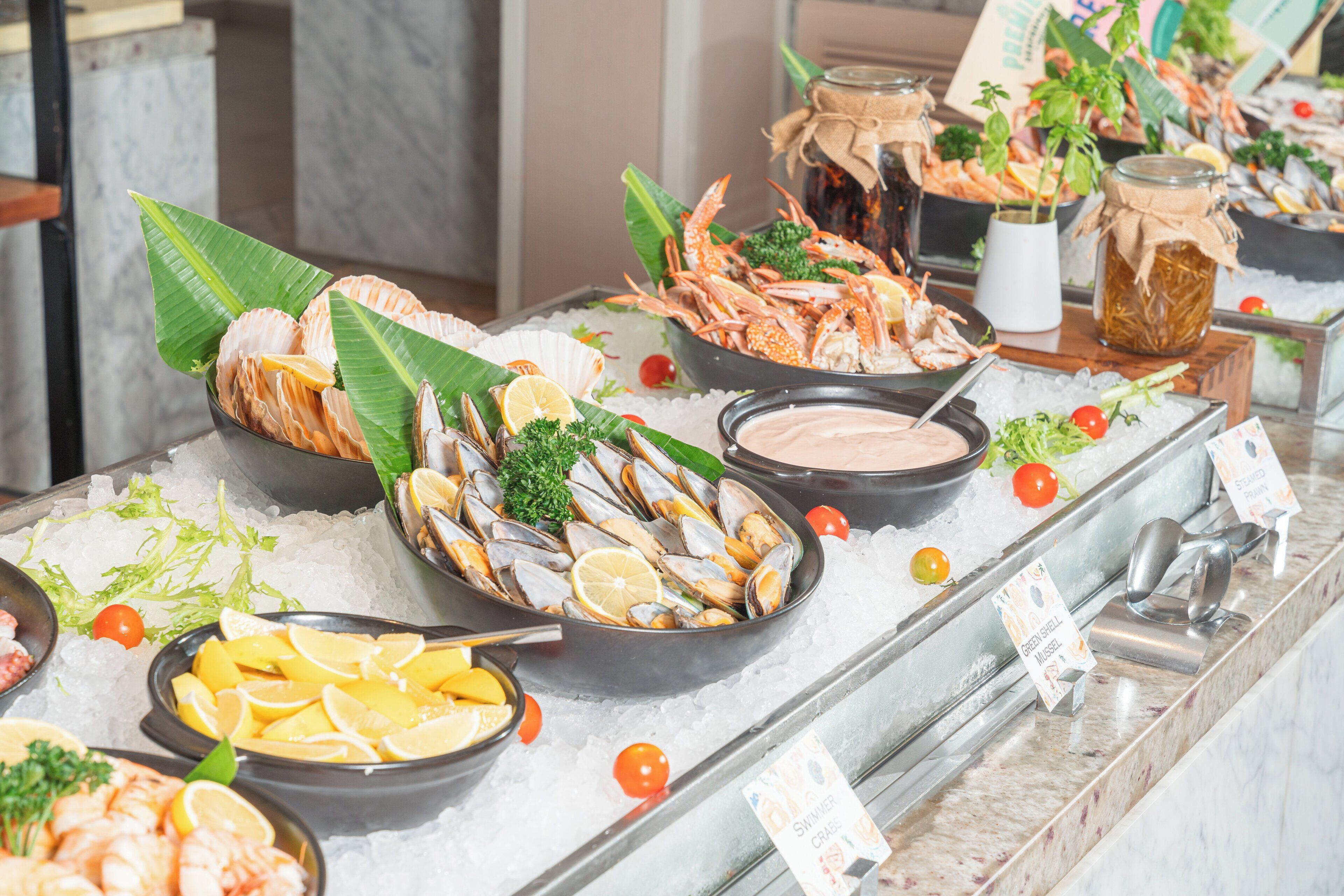 Un présentoir de fruits de mer avec divers crustacés et accompagnements, le tout disposé sur de la glace.