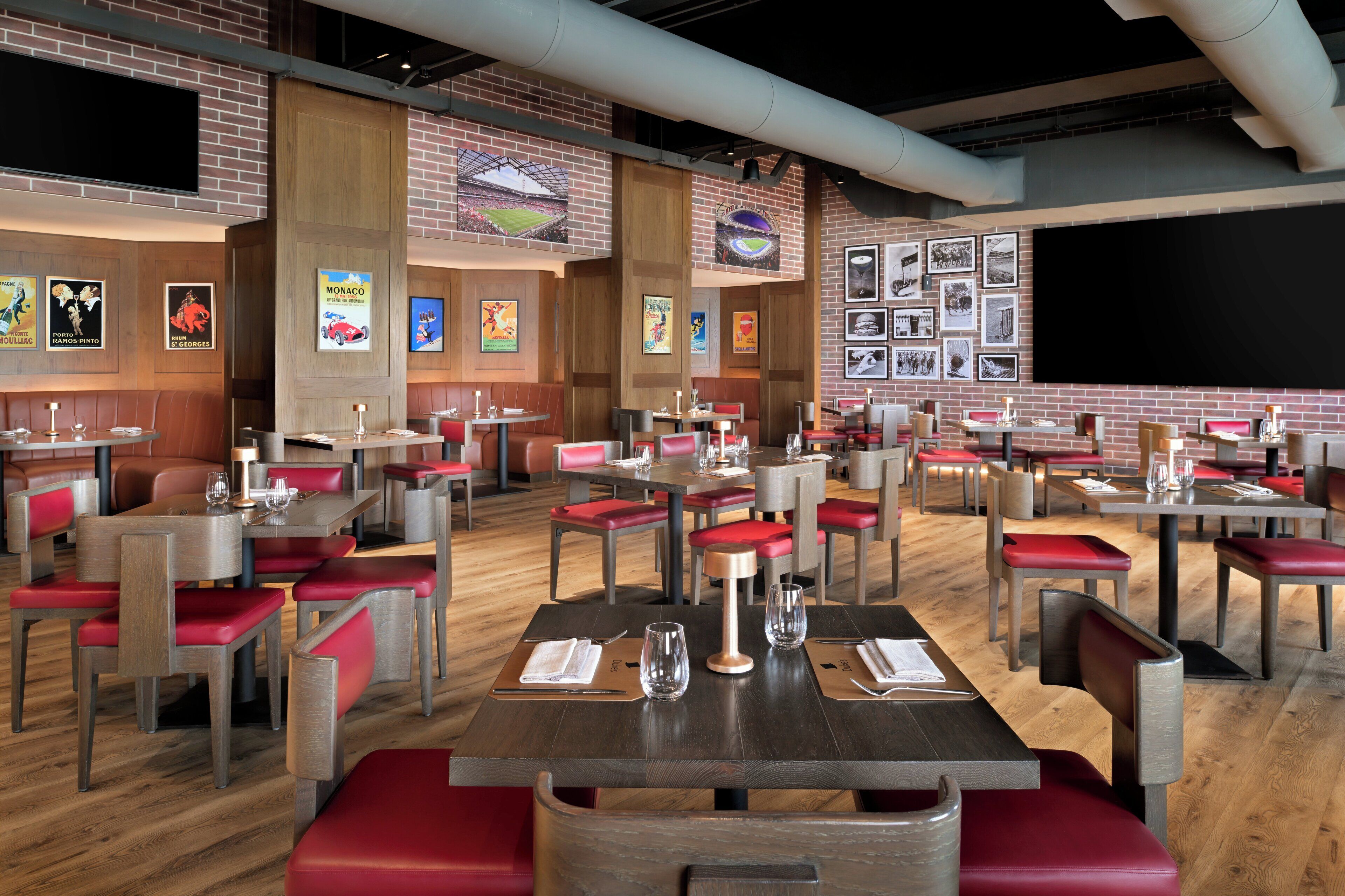 A restaurant with multiple tables and booths, wooden floors, and brick walls.