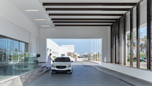 A modern building entrance with a white car parked inside, large windows, and a clear view of the sky.