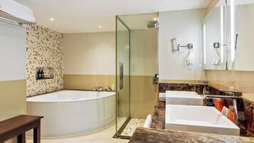 A modern bathroom with a large bathtub, a glass-enclosed shower, and two sinks.