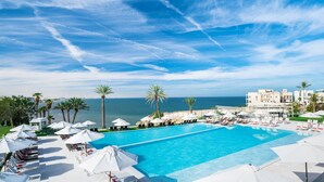 A pool area with lounge chairs and umbrellas, overlooking a beach and ocean.