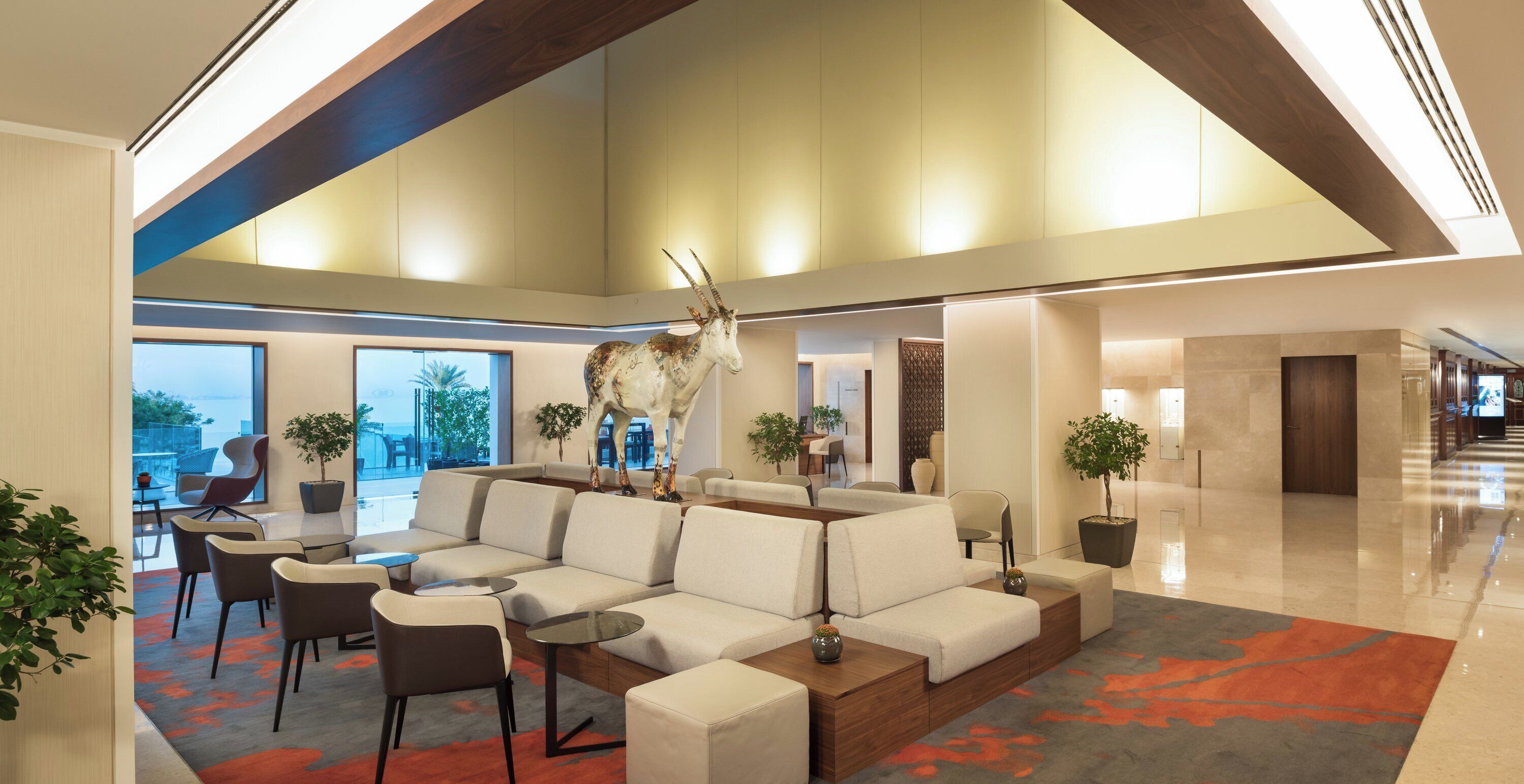 A modern lobby with a seating area, a large decorative sculpture, and a view of the outdoors.