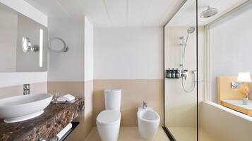 A modern bathroom with a marble sink, a toilet, a bidet, and a glass-enclosed shower.