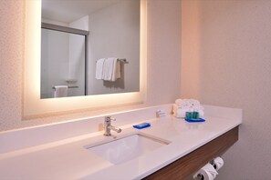 A bathroom with a white sink, a mirror, and a towel rack. - Holiday Inn Express Madera - Yosemite Park Area by IHG (Madera)