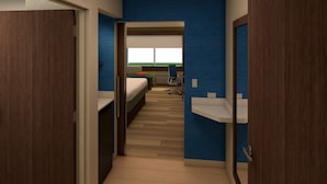 A hotel room with a bed, a desk, a chair, and a window with a view of the outdoors.