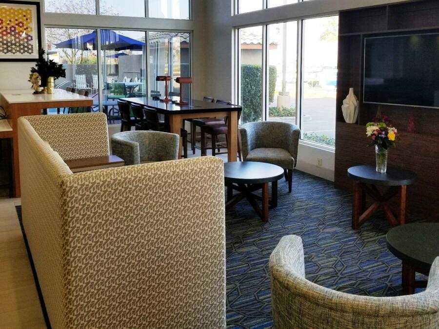 A hotel lobby with a bar area, seating arrangements, and a television screen.