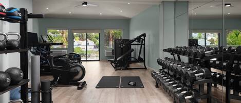 A gym with exercise equipment, a treadmill, and a bench.