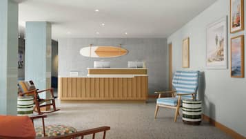 A reception area with a wooden reception desk, two chairs, a patterned armchair, and a wall with framed artwork.