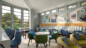 A restaurant with a view of greenery, a ceiling fan, and a wall with framed pictures.