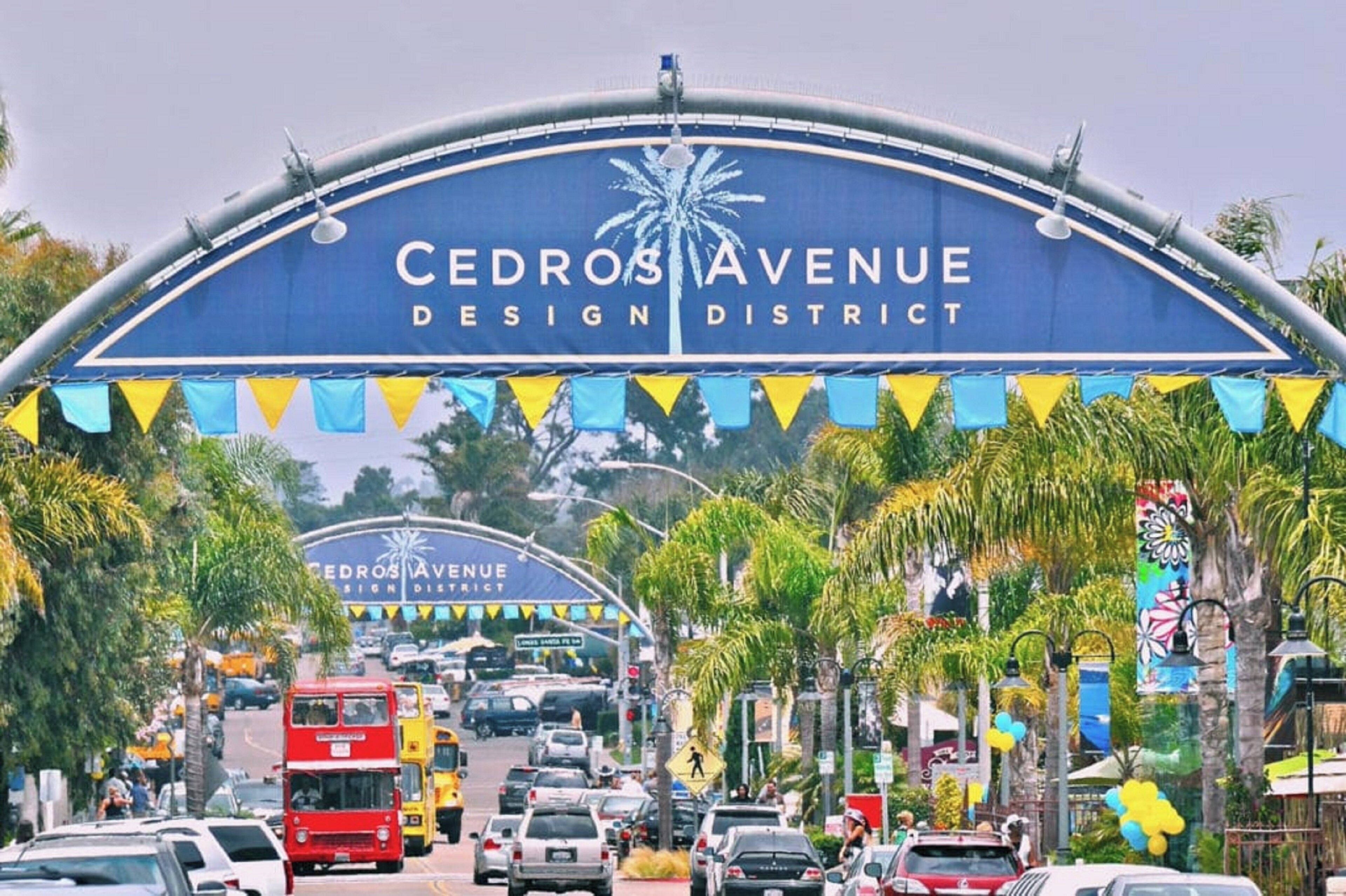 Un panneau de signalisation indiquant le « quartier du design de Cedros Avenue », avec un ciel dégagé et des palmiers en arrière-plan.