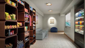 A modern interior with a snack bar, seating area, and a refrigerator stocked with beverages.