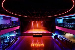 A theater with a stage, seating, and a bar area.