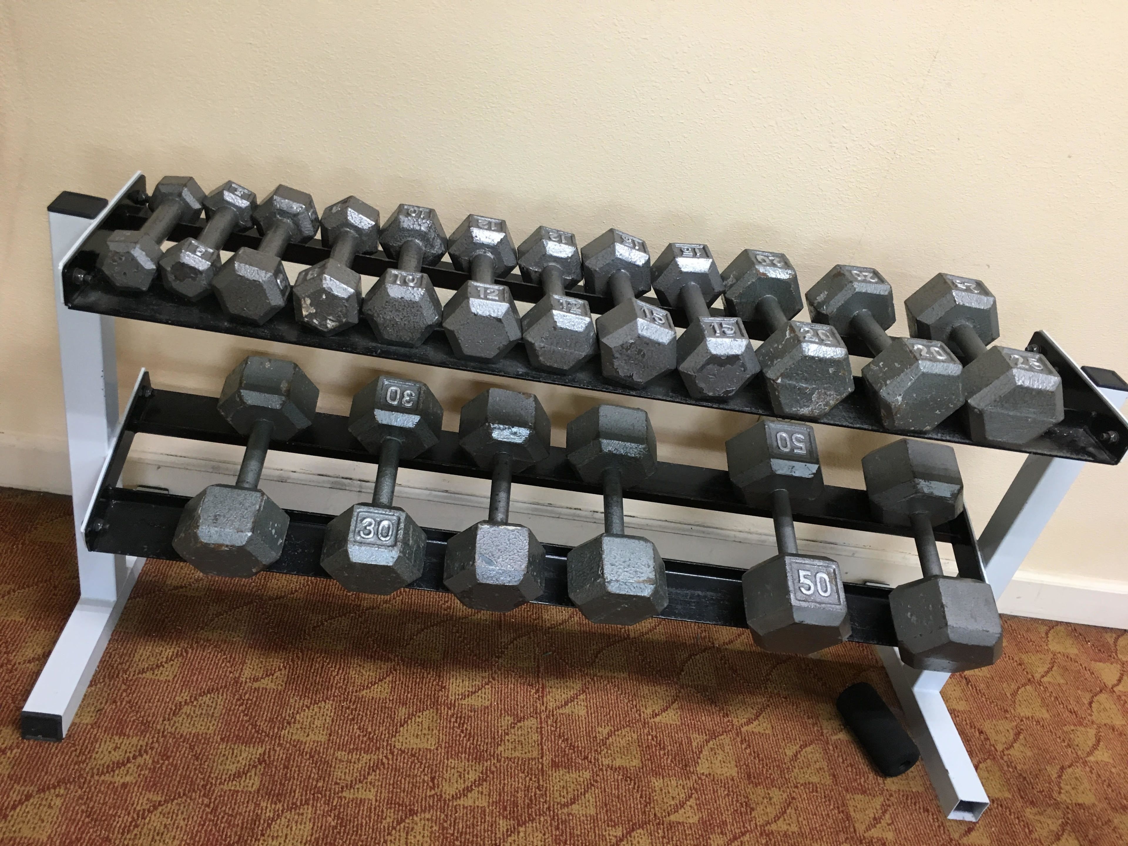 A set of dumbbells on a rack with weight markings.