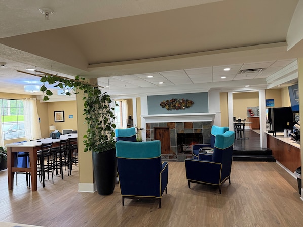 A hotel lobby with a fireplace, seating area, and a reception desk.