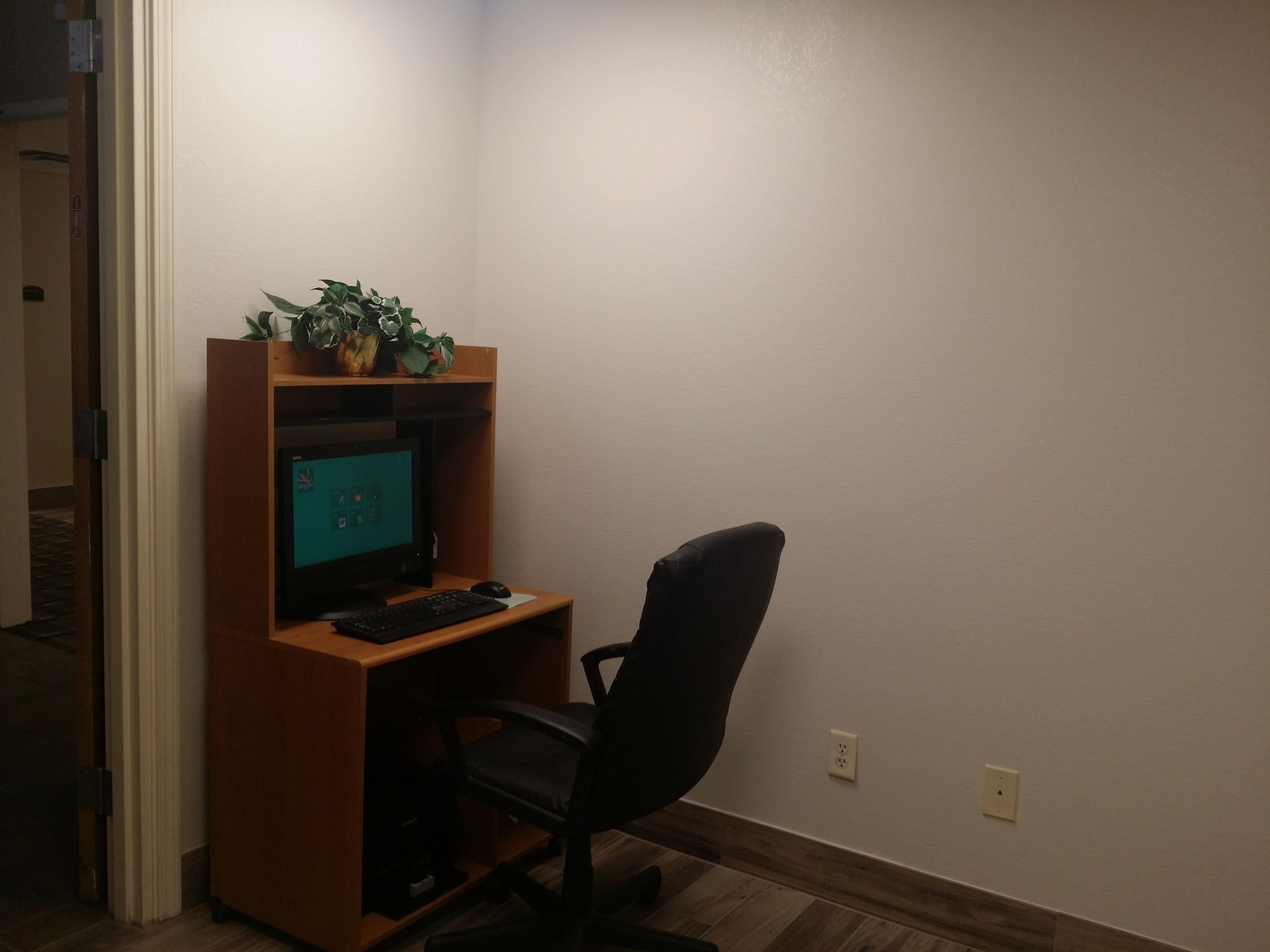 Un pequeño espacio de oficina con un escritorio, computadora, silla y una planta en maceta.