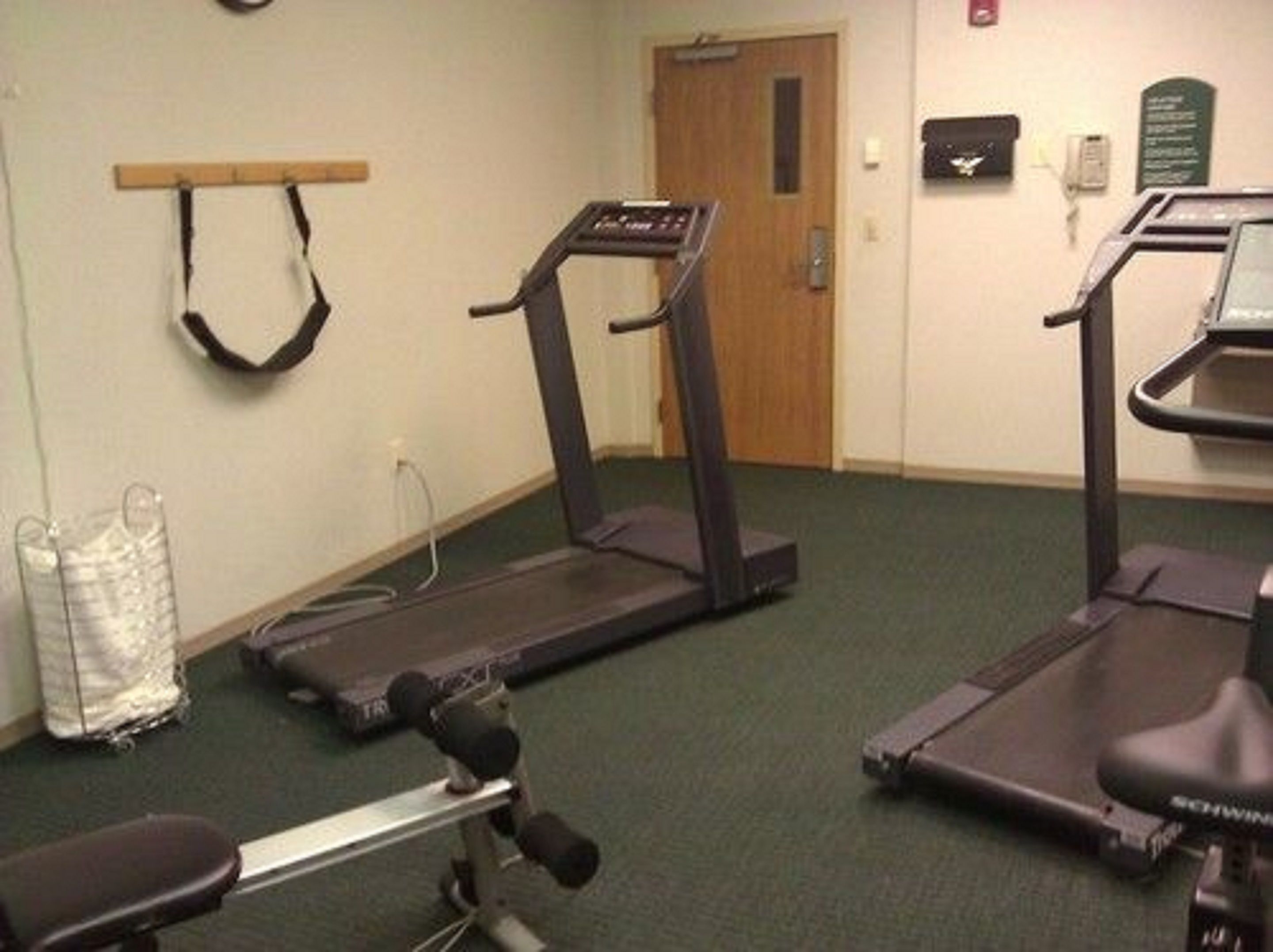 A fitness room with treadmills, a bench, and a water bottle.