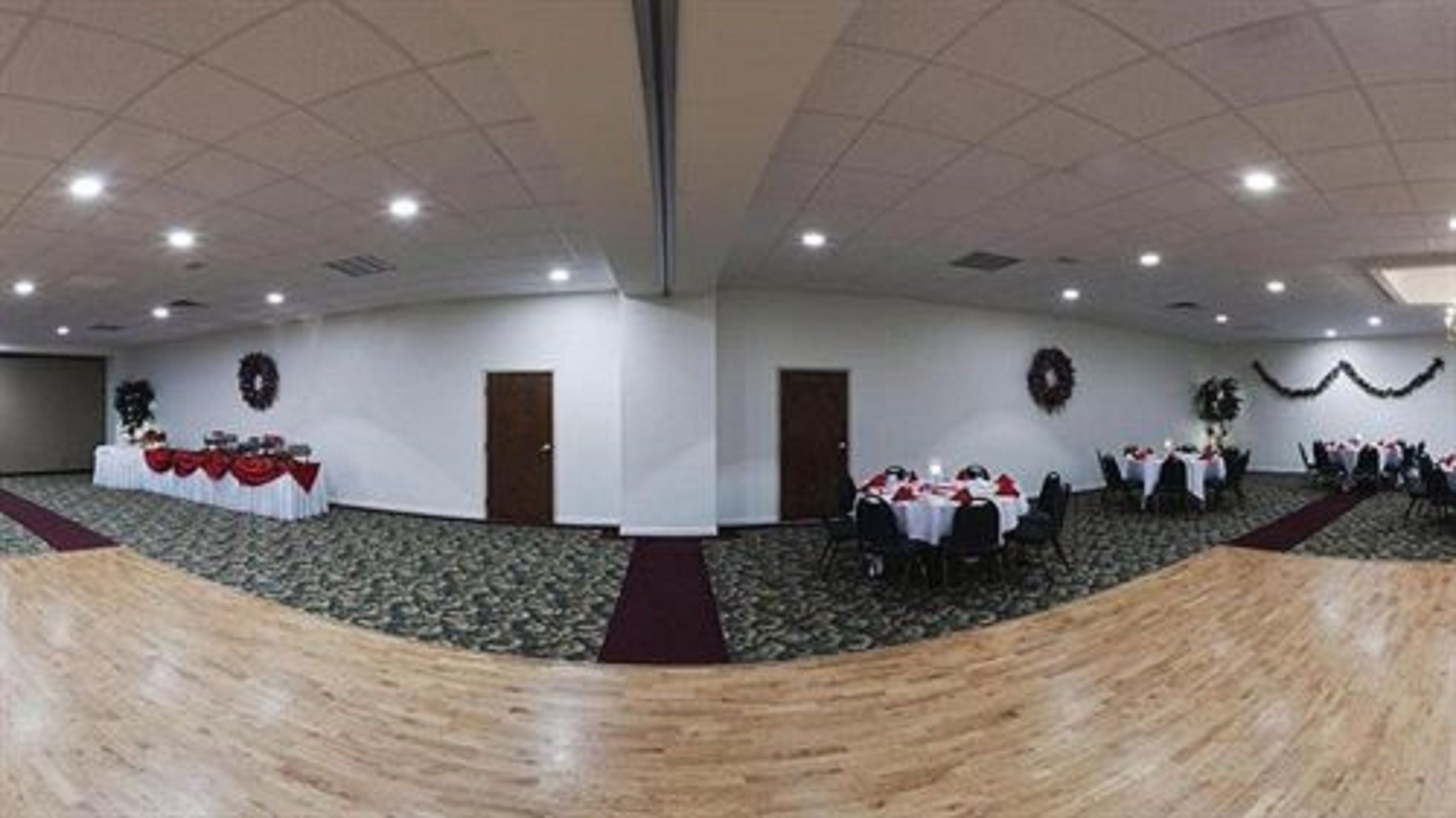 A large, well-lit conference room with a high ceiling and carpeted floor, featuring tables set for a formal event.