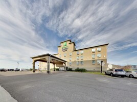 Un hotel Holiday Inn Express & Suites con un estacionamiento y cielo despejado.