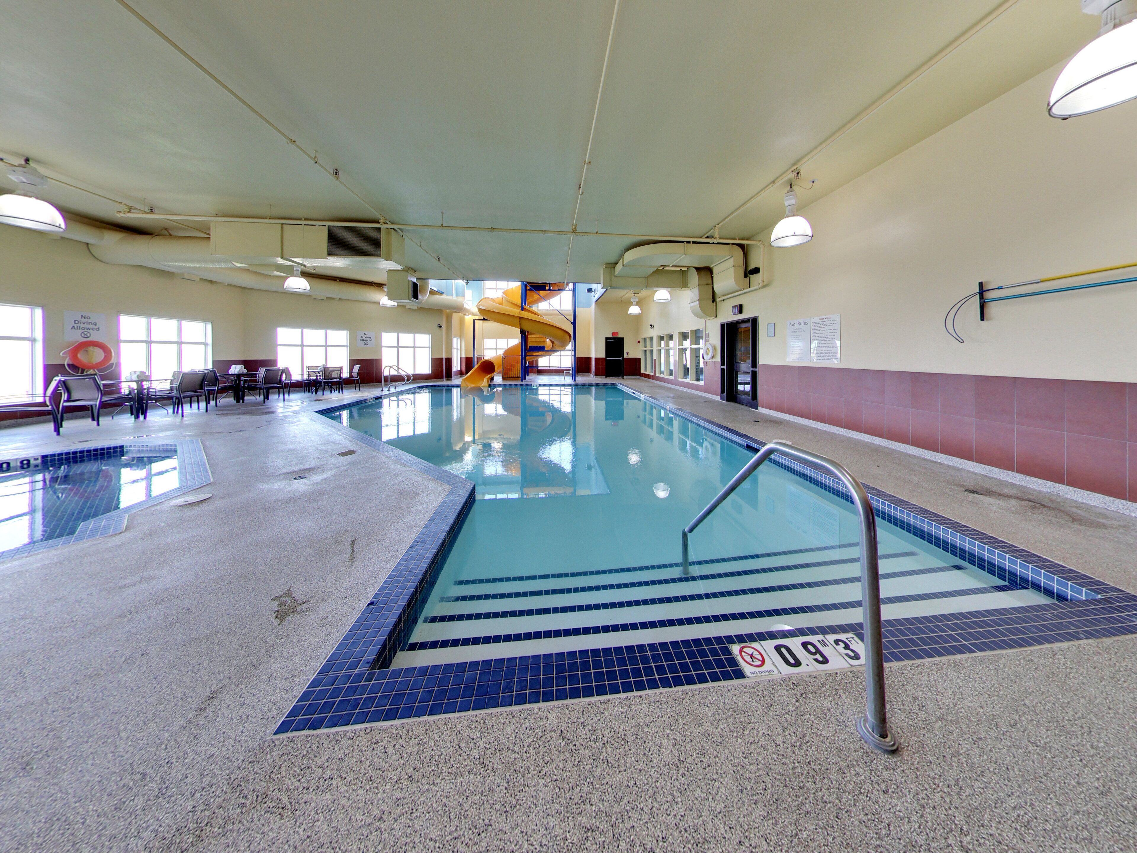 An indoor swimming pool with a no diving sign, a water slide, and a lifeguard chair.