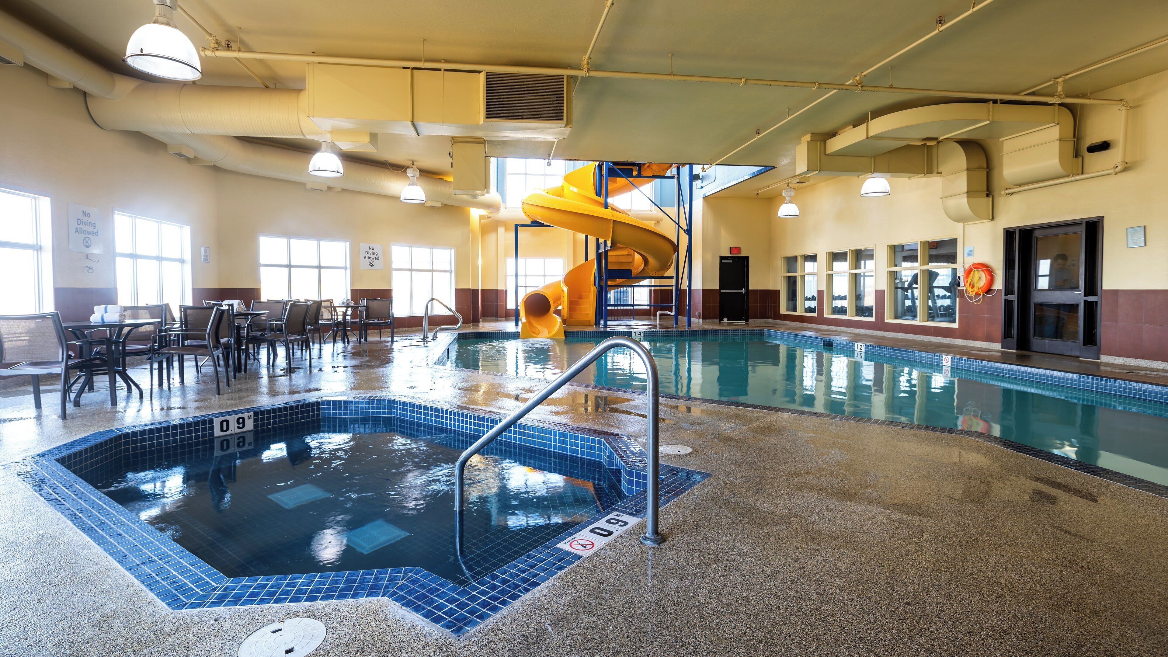 An indoor swimming pool with a slide, seating area, and lifeguard station.