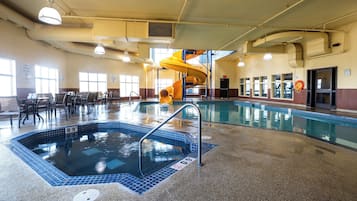 An indoor swimming pool with a slide, seating area, and lifeguard station.