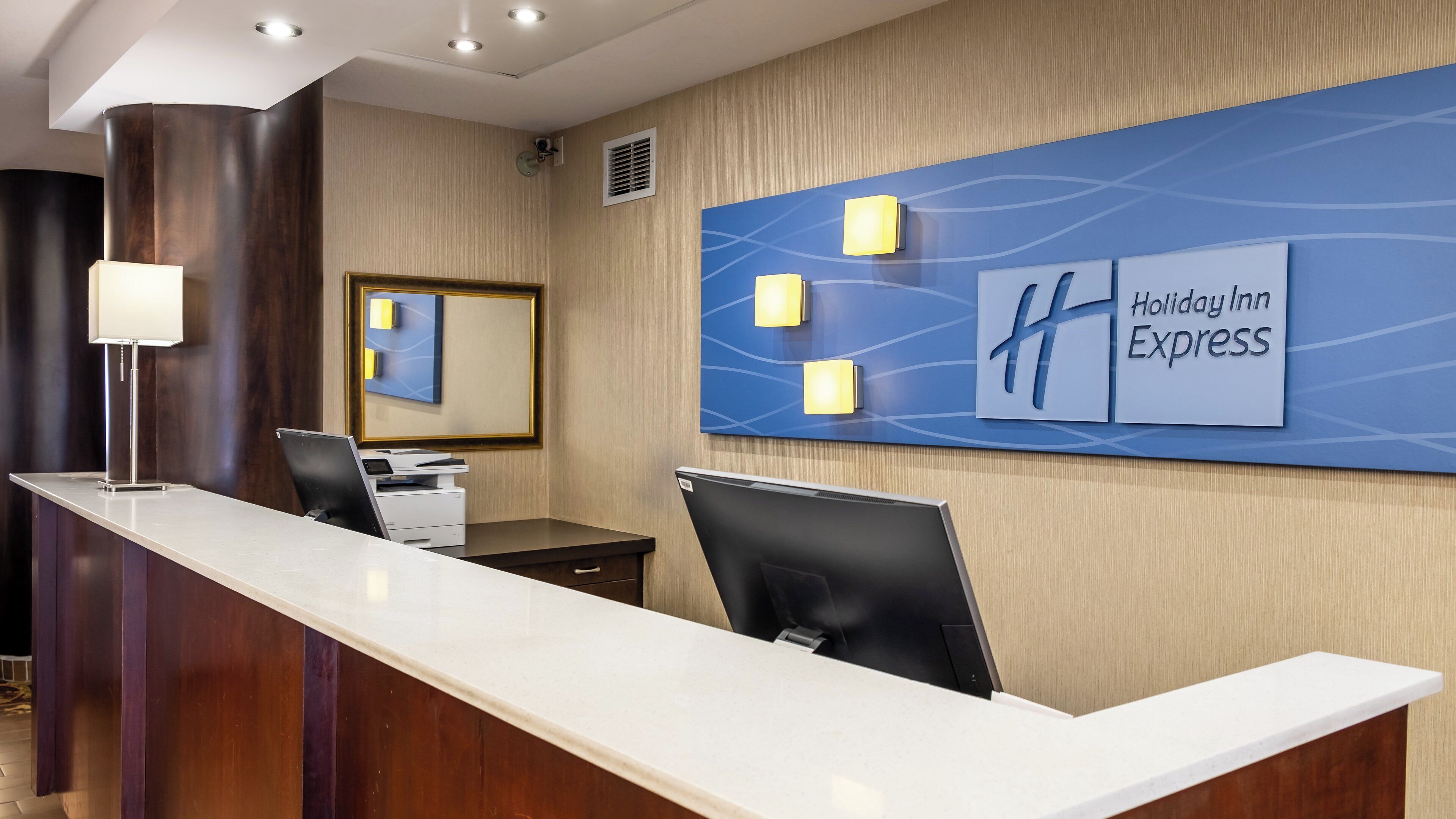 A hotel reception desk with a modern design, a digital display, and a sign for Holiday Inn Express.