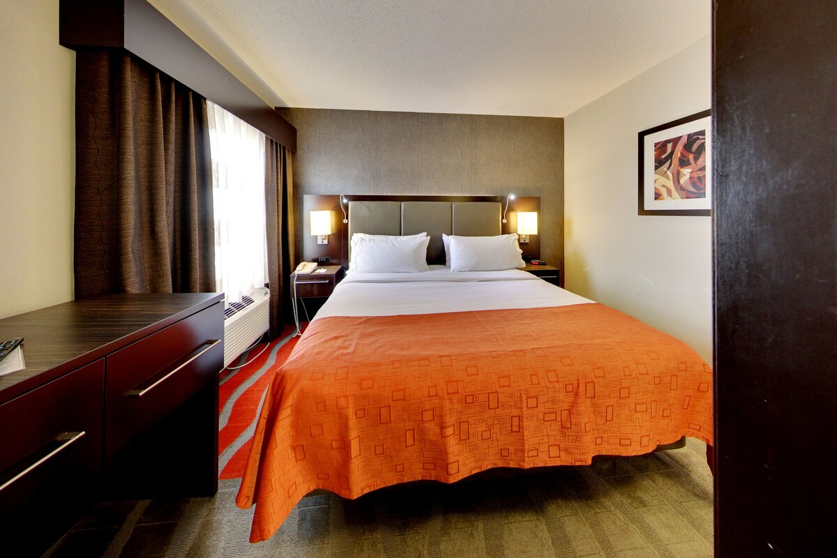 A hotel room with a bed, bedside tables, a desk, and a chair.