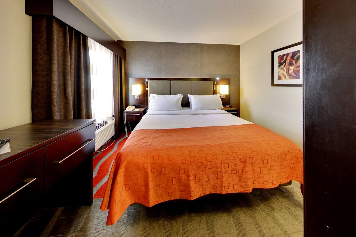 A hotel room with a bed, a desk, a telephone, and a nightstand.
