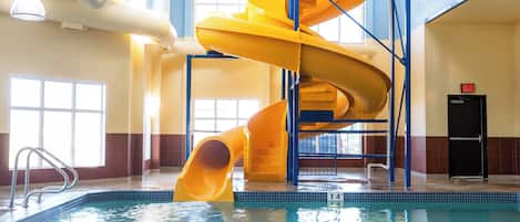 Zona de piscina con un tobogán en espiral amarillo y una piscina cristalina.