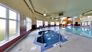 An indoor swimming pool with a blue tiled floor, a diving board, and a slide. - Holiday Inn Express & Suites Edmonton International Airport by IHG (Nisku)