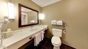 A hotel bathroom with a white sink, a toilet, a large mirror, and a towel rack.