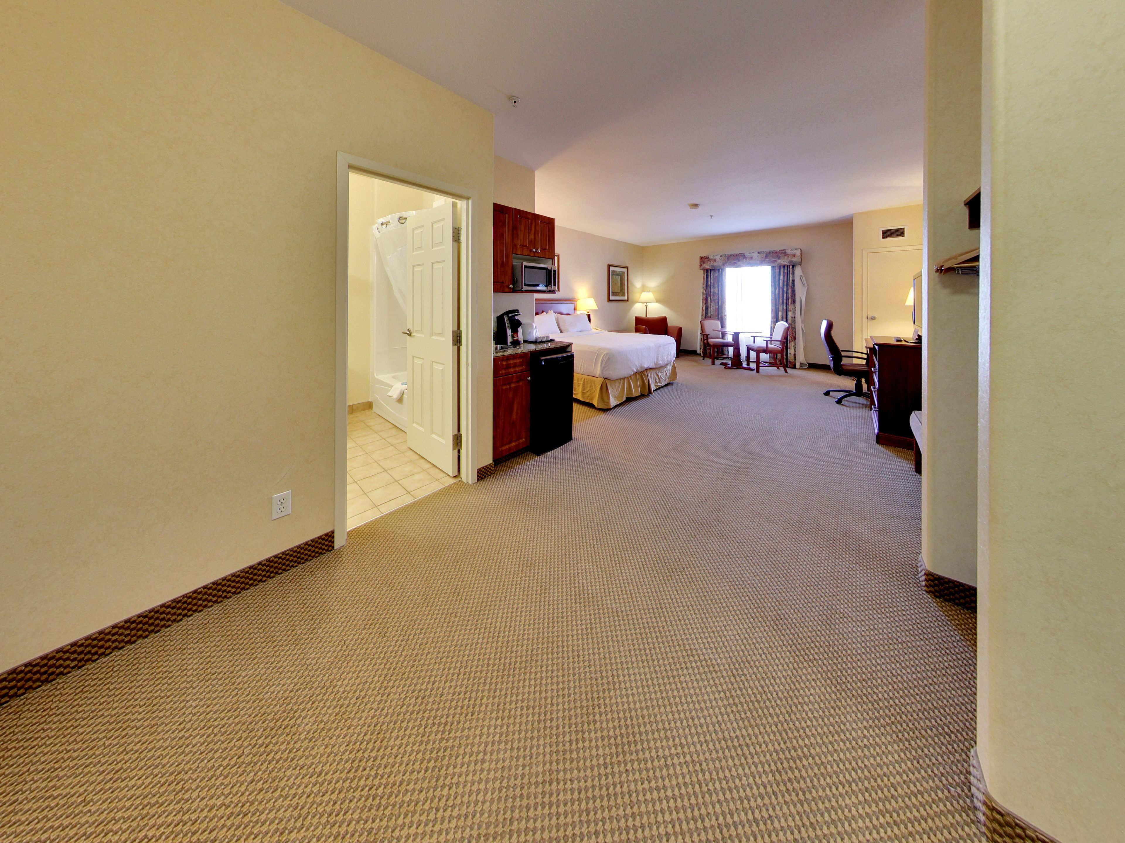 A hotel room with a bed, a desk, a chair, a television, and a bathroom.